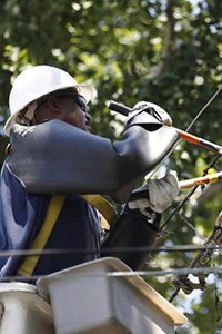 An electrical worker cuts a damaged overhead power line during emergency repairs in Wheaton